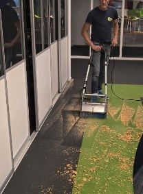 Tapijt wordt gereinigd met de Dry Carpet Cleaning-machine; het gereinigde deel is zichtbaar lichter